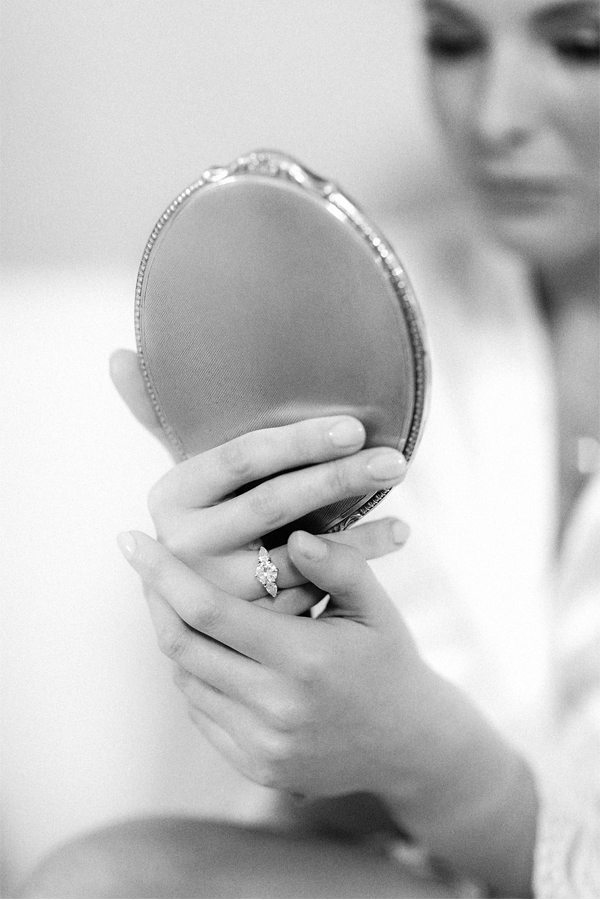 bride looking at a mirror with engagagment ring