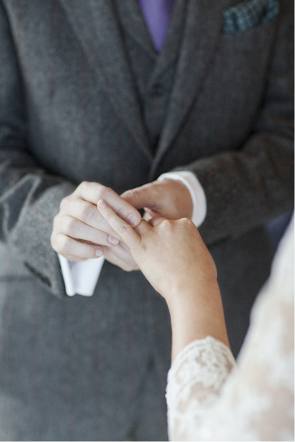 groom puting a wedding ring on bride