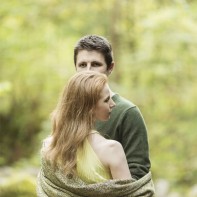 engaged couple in a forest in scotland holding each other with shawl