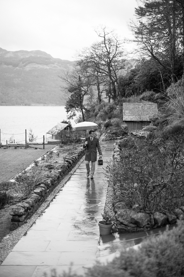 groom walking in the rain for ceremony at the lodge on loch goil scotland