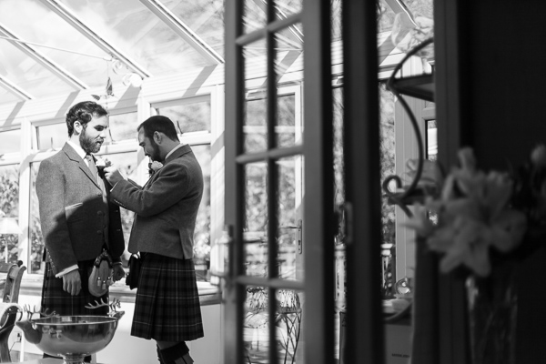 groom having his button whole fixed by best man