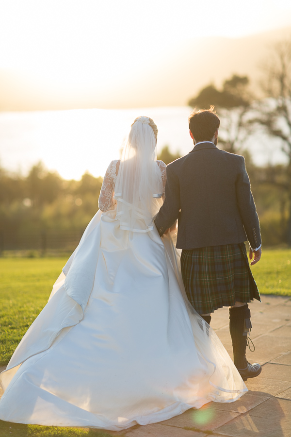 newlyweds walking away towards loch lomond and sunset