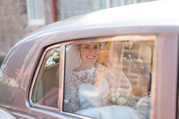 bride waving to teh guests leaving