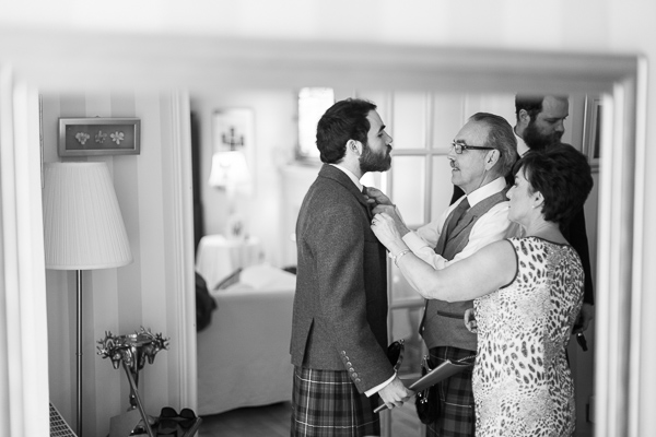 groom having his tie fixed by parents