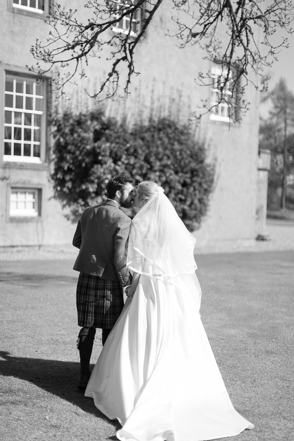 newlyweds kissing while walkng away towards boturich castle
