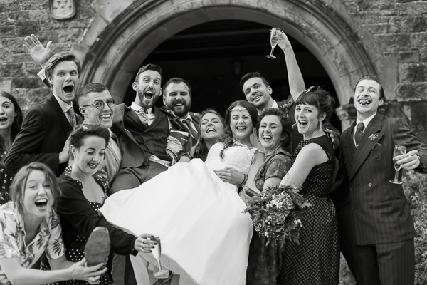 friends going crazy at wedding lifting bride and groom