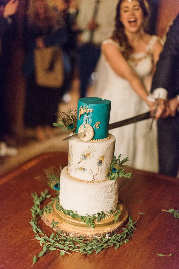 wedding cake beeing cut with a sword