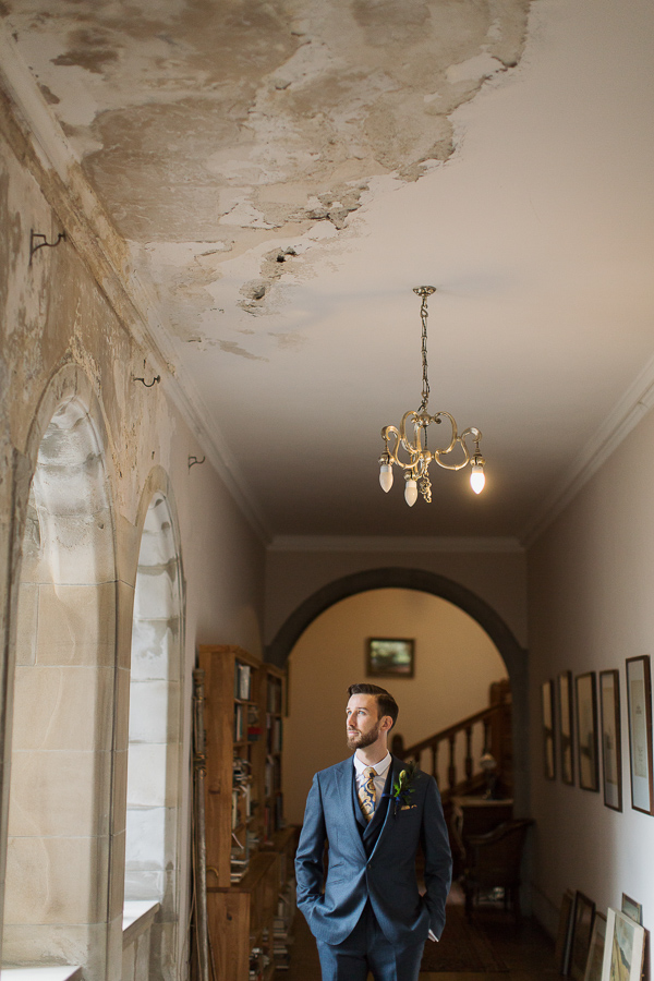 groom looking through the windo at weddign venue near glasgow scotland