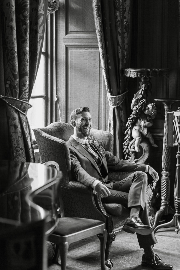 groom laughing sitting on a char at arkinglas estate hall