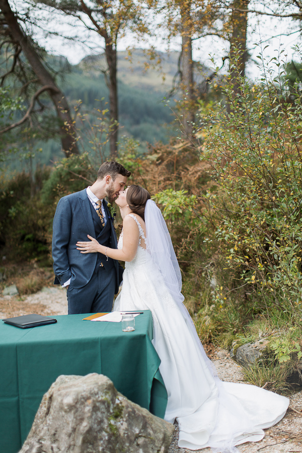 bride and groom kissing before signing paper work during ceremony
