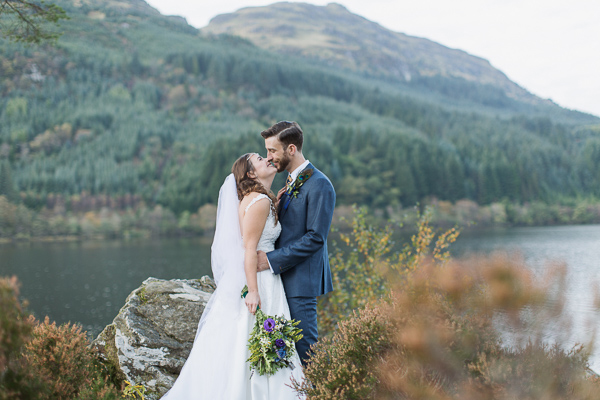 bride and groom embraced on top of a hill at loch eck near glasgow