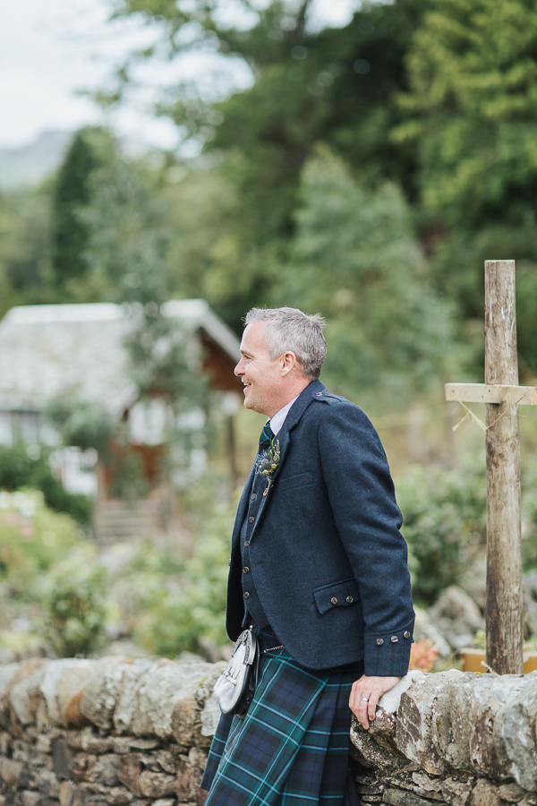 groom sitting on a brick wall