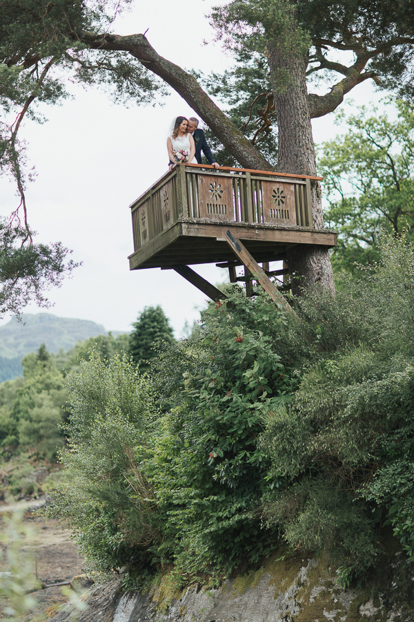 bride and groom embraced on a tree podium