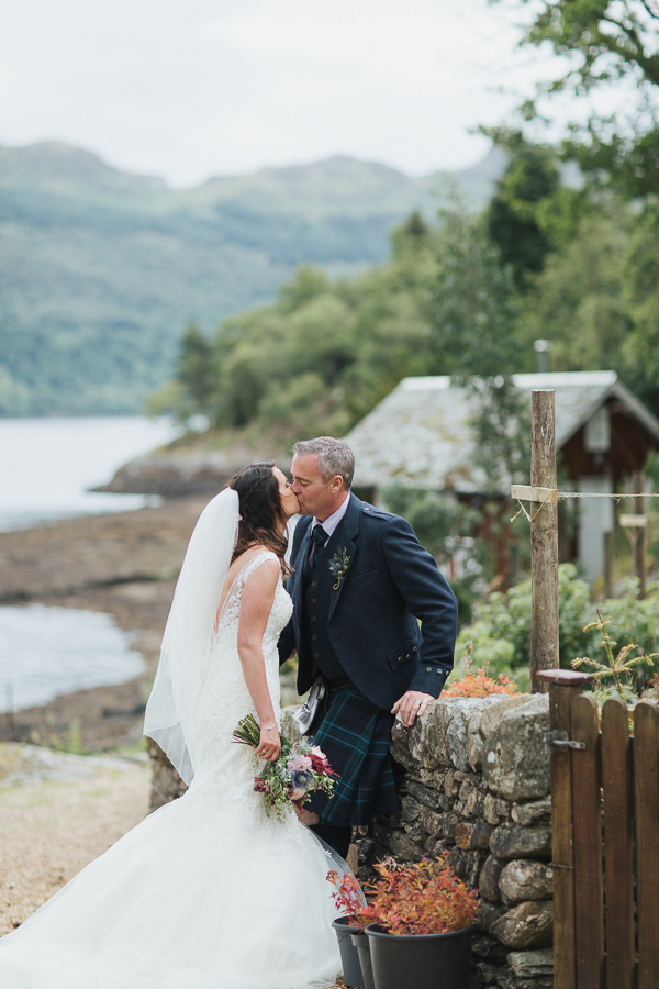 newlyweds kissing in a garden of at the lodge on loch goil