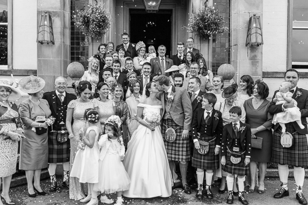 family photo with newlyweds kissing