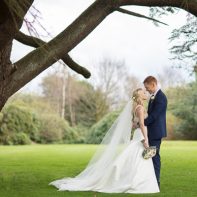 young married coupke standing under large tree mar hall wedding
