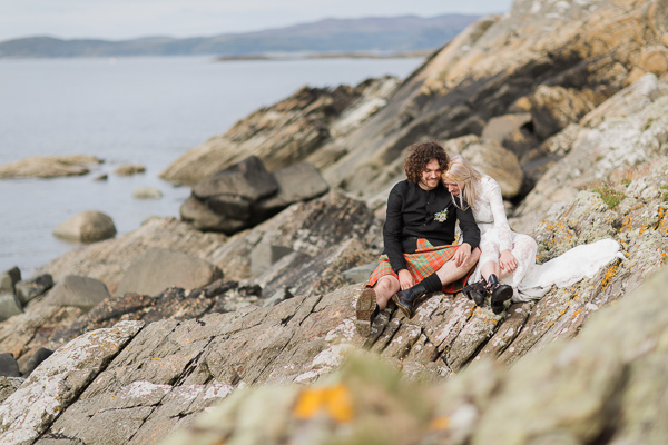 bride and groom sitting on a rocky coast