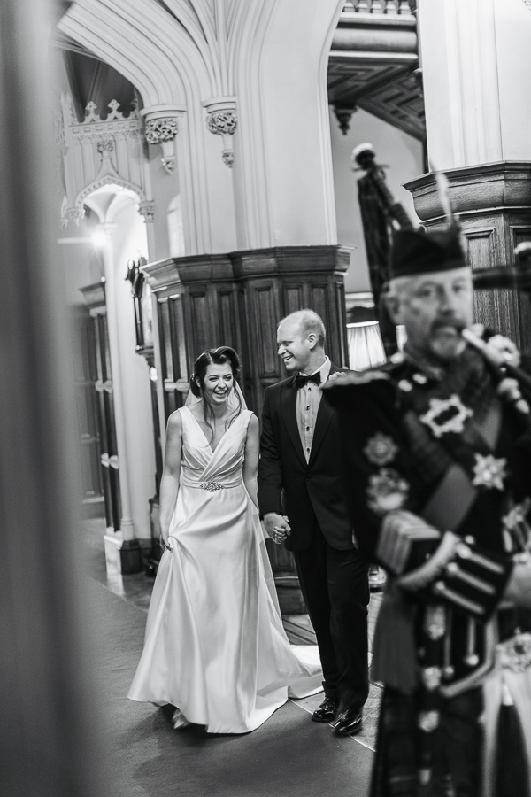 bride and groom laughing beeing leaded by scottish piper
