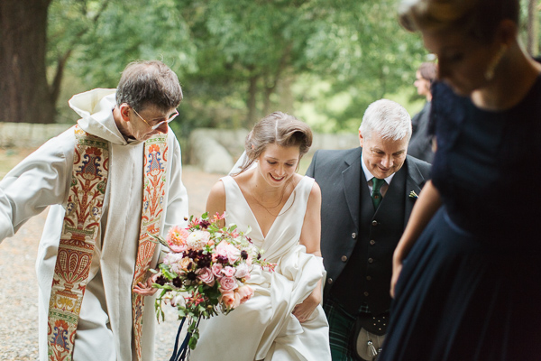 bride walking in to teh church with father and minister