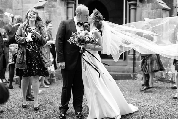 fotogenic of scotland bride and groom kissing outside church in scotland veil is lifted by wind