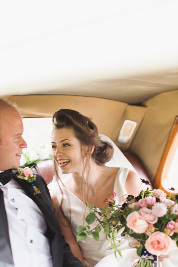bride smiling at groom inside the wedding car