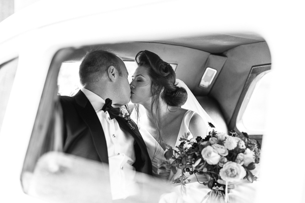 newlyweds kissing inside wedding car
