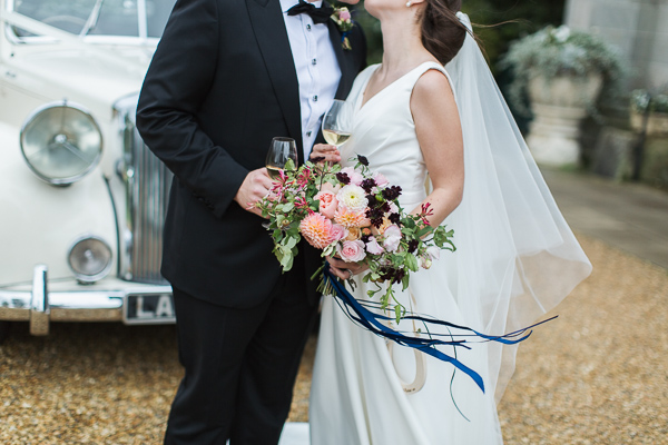 bride and groom embraced kissing holding champagine glasses