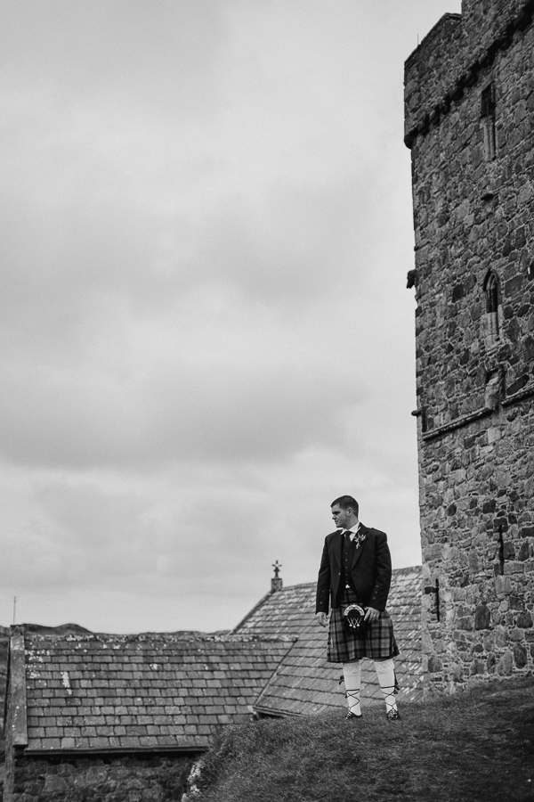 groom satanding on a hill next to the rodel church