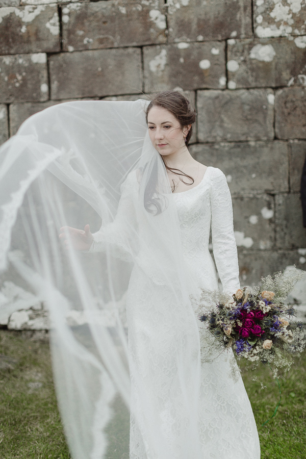 bride trying to catch her veil on the wind