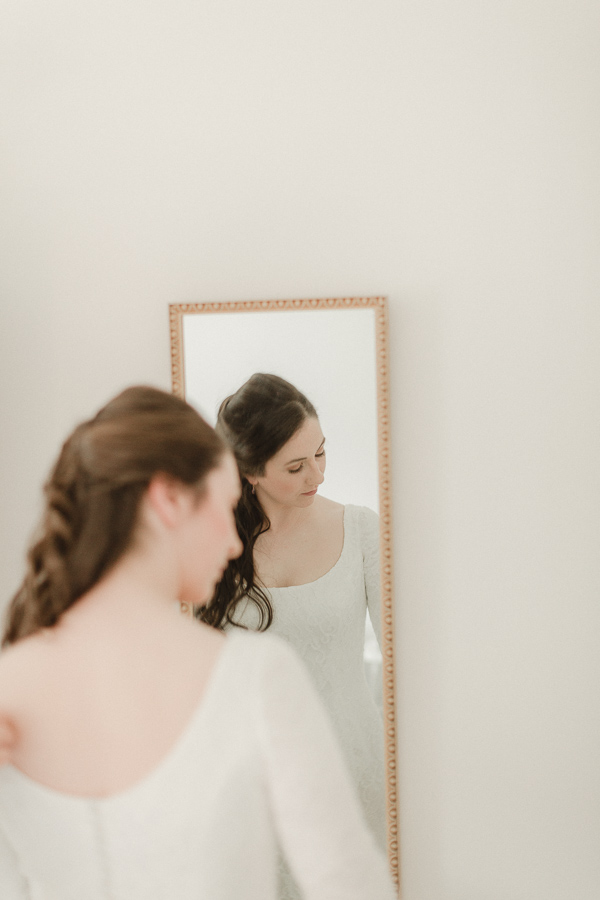 bride fixing her hair during preparations at home