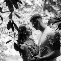 young couple embraced betwen leaves in summer engagement photos