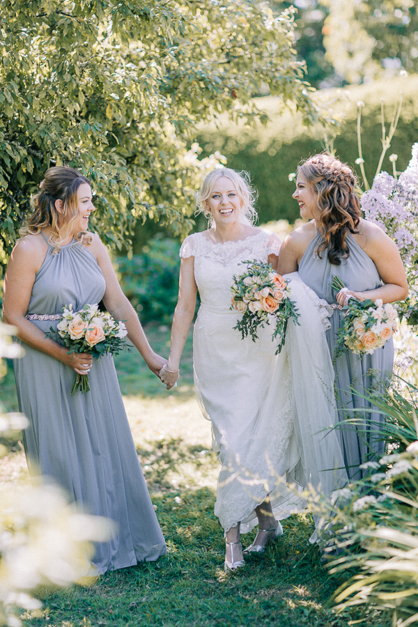 bride smiling and hloding hands with bridesmaids loch lomond 