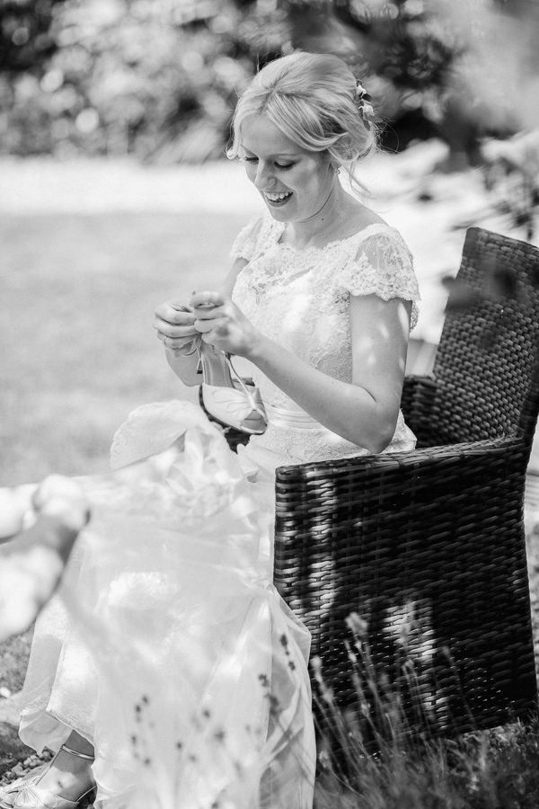 bride in her garden puttign her shoes on 