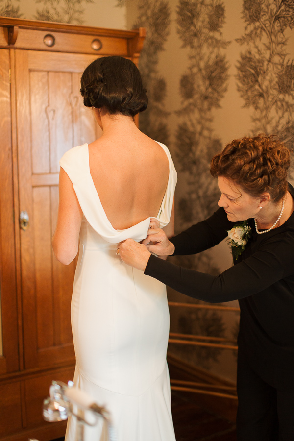 mother of the bride zipping the wedding dress