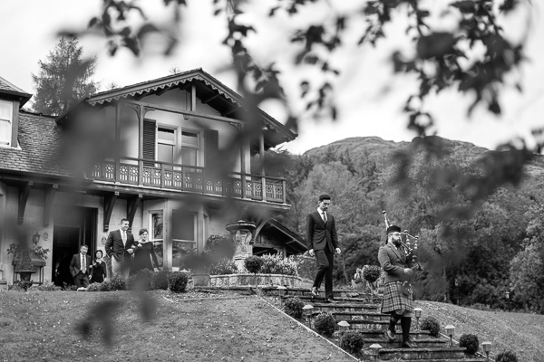 piper is leading groom and guests for tree house ceremony at loch goil