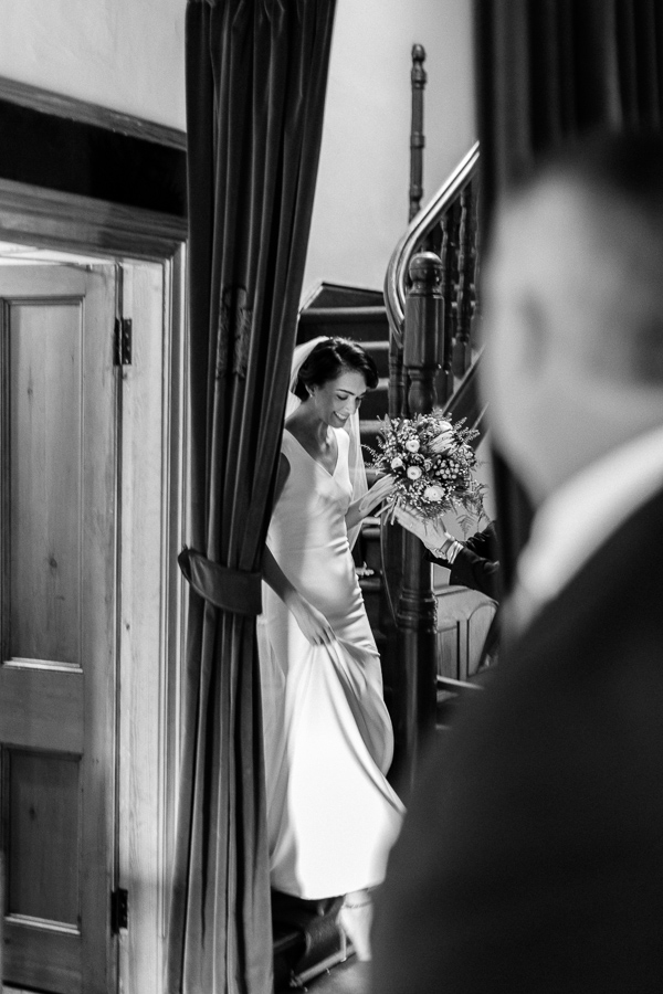 bride walking down stairs while father is looking