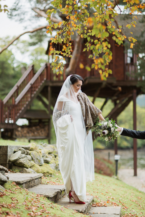 bride beeing held by her hand by groom in the ground of the lodge on loch goil