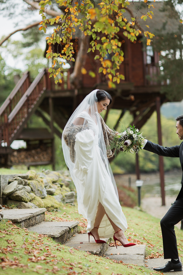 bride walking down with help of groom at the lodge gardens