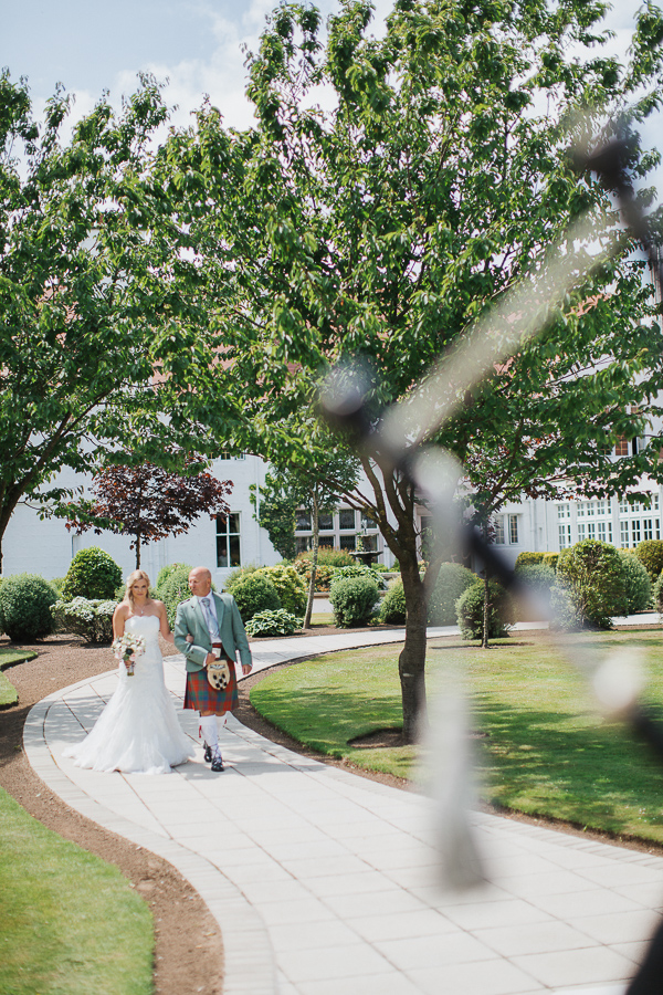 bride walking down in teh garden for ceremony at lochgreen hotel