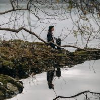 girl sitting on the edge of lake with reflexion scotland