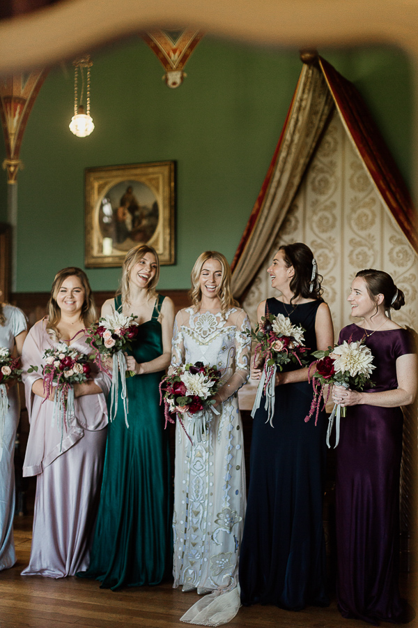 reflection in teh mirror of bridesmates laughing holding flowers